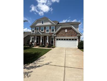 Charming two-story home boasts a manicured lawn and inviting facade with stone and gray siding and a two car garage at 2810 Shumard Dr, Gastonia, NC 28054