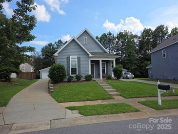 Charming blue home with a well-manicured lawn, inviting front porch, and detached garage at 4032 Wilgrove Way Dr # 252, Charlotte, NC 28213