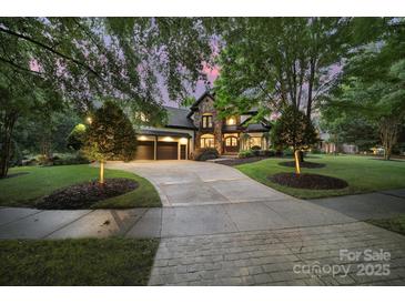 Stunning stone-accented home with well-manicured lawn, mature trees, and a spacious driveway leading to a three-car garage at 8016 Pemswood St, Charlotte, NC 28277