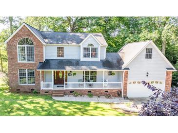 Charming two-story home with brick accents, a front porch with white railings and manicured lawn and mature landscaping at 110 Club Dr, Mooresville, NC 28115