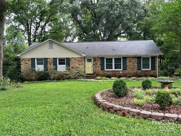 Charming brick ranch-style home with a lush green lawn and well-manicured garden featuring a delightful bird bath at 11329 Torino Rd, Matthews, NC 28105