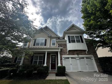 Charming two-story home featuring a stone facade, attached garage, and manicured landscaping at 1386 Secret Path Dr, Fort Mill, SC 29708