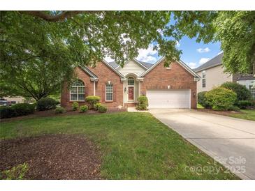 Charming brick home with mature trees, landscaped yard, and a two-car garage on a sunny day at 14103 Hiawatha Ct, Huntersville, NC 28078
