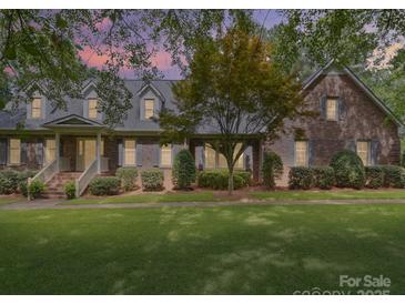 Charming brick home featuring a well-manicured lawn and inviting front porch, set beneath a colorful dusk sky at 394 E Goldmine Rd, Wadesboro, NC 28170
