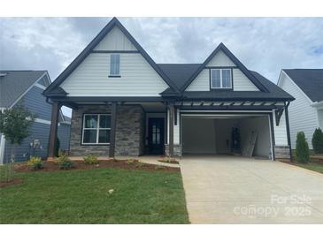 Charming two-story home featuring a stone facade, open garage, and a well-manicured lawn at 5578 Caneel Ln # 1227, Denver, NC 28037
