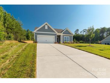 Charming home with gray siding, manicured lawn, and a long concrete driveway leading to an attached two-car garage at 10180 Lakeshore Dr, Lancaster, SC 29720