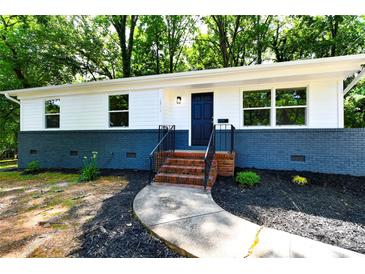 Charming renovated ranch-style home featuring a white exterior with a blue brick foundation and black door at 1513 Greenview Pl, Charlotte, NC 28208