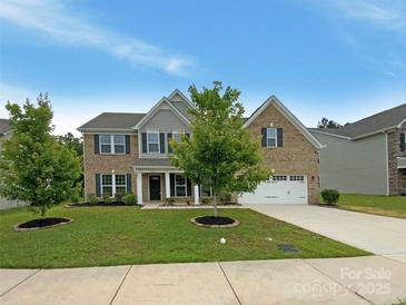 Charming brick two-story home featuring a manicured lawn, inviting front porch, and attached two-car garage at 2382 Drake Mill Sw Ln, Concord, NC 28025
