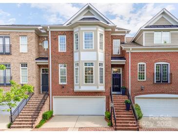 Charming brick townhome featuring an attached two-car garage and lovely front entrance with decorative windows at 3036 Luke Crossing Dr, Charlotte, NC 28226