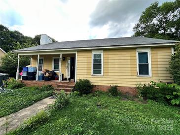 Quaint yellow home featuring a covered porch with storage and a small front yard at 3396 Farm Lake Sw Dr, Concord, NC 28027