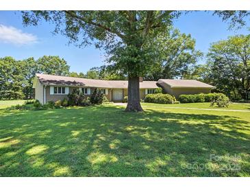 Spacious front yard with lush green lawn and mature shade trees enhancing curb appeal on a sunny day at 13909 Idlewild Rd, Matthews, NC 28105