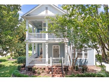 Charming two-story home with a welcoming double porch and light blue siding surrounded by lush landscaping at 15838 Trenton Place Rd, Huntersville, NC 28078