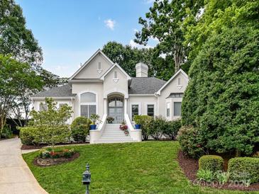Beautiful white home featuring a well-manicured lawn and lush, mature landscaping surrounding the property at 19205 Hidden Cove Ln, Cornelius, NC 28031