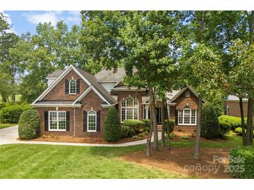 Charming brick home with mature trees, lush landscaping, and manicured lawn at 2241 Flagstick Dr, Matthews, NC 28104