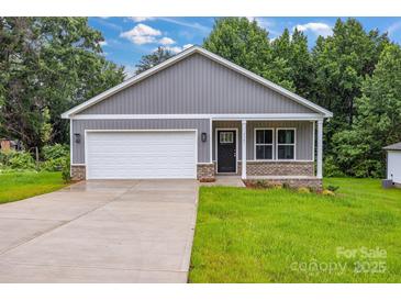 Charming single-story home featuring a covered porch, gray siding, and a two-car garage at 5185 Grand Canyon Rd, Concord, NC 28027