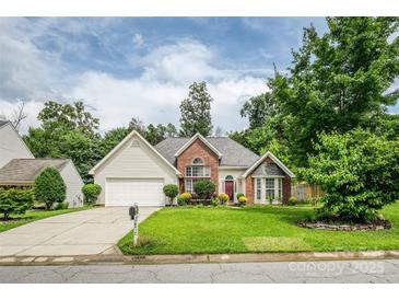 Charming brick and vinyl home featuring a lush, well-manicured lawn and mature trees at 6414 Goldenblush Cir, Charlotte, NC 28269
