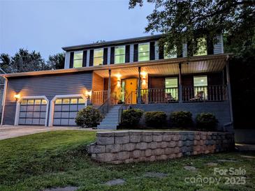 Charming two-story home featuring an attached two-car garage and a welcoming front porch with a yellow door at 11419 Leadenhall Ln, Charlotte, NC 28262