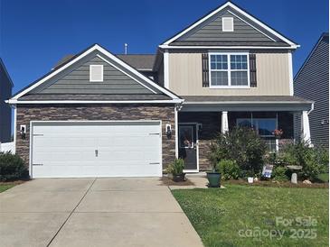 Charming two-story home with stone accents, a two-car garage, and a well-maintained front yard at 1220 Kent Downs Sw Ave, Concord, NC 28027