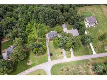 An aerial view of a property nestled among trees, featuring a long driveway and expansive lawn at 3874 Willow Grove Ln, Concord, NC 28025