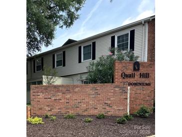 Exterior view of condo with brick base, gray siding, and black shutters in a meticulously maintained community at 5941 Quail Hollow Rd # F, Charlotte, NC 28210