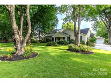 Inviting home featuring a lush green lawn, mature trees, and manicured landscaping at 802 E Franklin St, Monroe, NC 28112