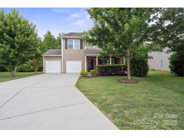 Charming two-story home featuring a two-car garage, well-manicured lawn, and mature trees at 1210 Tabitha Ct, Monroe, NC 28110