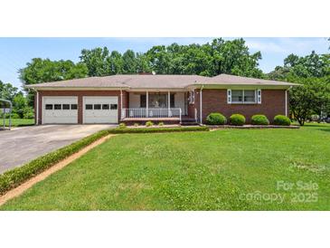 Charming brick home featuring an attached two-car garage and a welcoming front porch at 128 Howie St, Mount Holly, NC 28120
