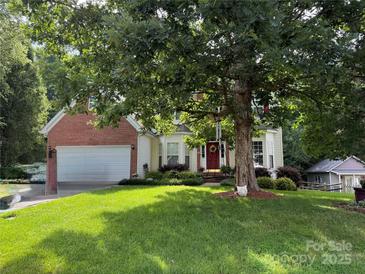 Charming two-story home with attached garage, red door, manicured lawn, and mature landscaping at 130 Nims Spring Dr, Fort Mill, SC 29715