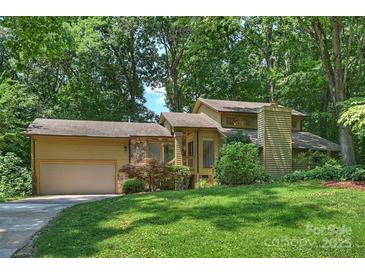 Charming home with a two-car garage, stone accents and lush landscaping, enveloped by mature trees at 1419 Jules Ct, Charlotte, NC 28226