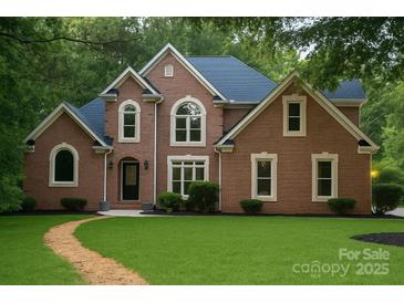 Charming brick home featuring lush lawn, manicured shrubbery, and complementary blue roofing at 3011 Mckee Rd, Charlotte, NC 28270