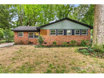 Charming brick home with a modern roof, large windows, and lush landscaping at 5320 Kildare Dr, Charlotte, NC 28215