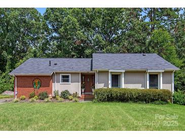 Charming ranch-style home features lush front lawn, mature trees and updated landscaping with detailed masonry facade at 5922 Sullins Rd, Charlotte, NC 28214