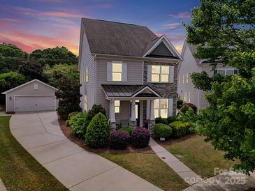 Charming two-story home with landscaped yard, stone accents, and detached garage at sunset at 8702 Aspinwall Dr, Charlotte, NC 28216