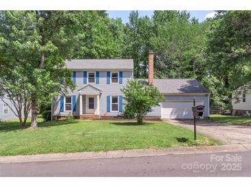 Charming two-story home with light gray siding, blue shutters, manicured lawn and mature trees at 2012 Killarney Pl, Charlotte, NC 28262