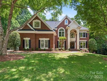 Beautiful brick home with a well-manicured lawn and mature trees, perfect for Gathering living at 610 Hampshire Hill Rd, Matthews, NC 28105