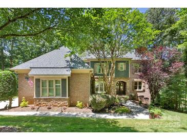 Charming brick home with a well-manicured lawn and lush landscaping, nestled beneath the shade of mature trees at 10007 Hillspring Dr, Huntersville, NC 28078