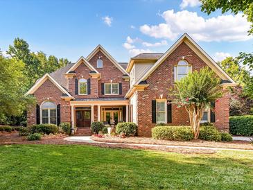 Charming brick home featuring lush landscaping, a manicured lawn, and a welcoming front porch at 15009 Fanning Manor Ct, Charlotte, NC 28277