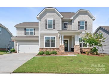 Charming two-story home featuring a manicured lawn, attached garage, and a welcoming front porch at 4116 Tory Path Rd, Waxhaw, NC 28173