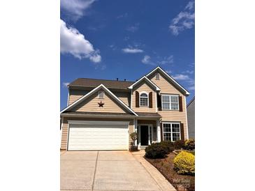 Charming two-story home featuring beige siding, a two-car garage, and a well-manicured front yard on a sunny day at 115 Morrocroft Ln, Mooresville, NC 28117
