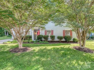 Charming home with a well-maintained front yard, lush lawn, mature trees, and an American flag at 4801 Pennant Pl, Charlotte, NC 28212