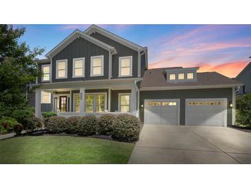 Beautiful two-story home with a two-car garage, a charming front porch, and manicured landscaping at twilight at 2052 Masons Bend Dr, Fort Mill, SC 29708