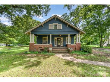 Charming blue home with inviting front porch and brick accents, surrounded by lush greenery at 6206 Hunter Ave, Charlotte, NC 28262