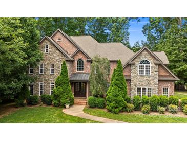 Stunning stone and brick home featuring mature landscaping and a meticulously maintained lawn at 6565 Robin Hollow Dr, Mint Hill, NC 28227