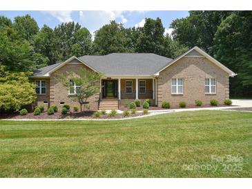 Charming brick home featuring a well-manicured lawn and inviting front porch with meticulous landscaping at 9117 Castle Garden Ln, Charlotte, NC 28215