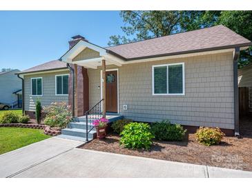 Charming home featuring neutral siding, landscaped garden beds, and a welcoming front entrance at 1005 Noles Dr, Mount Holly, NC 28120