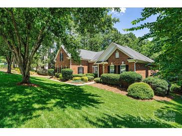 Charming brick home with lush green lawn, manicured landscaping, and mature trees providing shade at 1399 Verdict Ridge Dr, Denver, NC 28037
