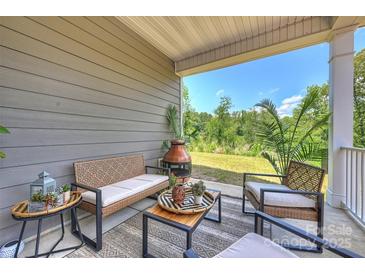 Inviting covered patio with stylish seating, outdoor rug, and views of the lush backyard at 336 Secretariat Dr, Iron Station, NC 28080
