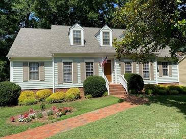 Charming one-story home featuring dormer windows, brick walkway, manicured lawn and mature trees at 6632 Summer Darby Ln, Charlotte, NC 28270