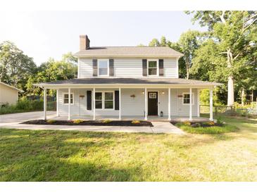 Charming two-story home with a welcoming front porch and well-maintained lawn surrounded by mature trees at 8012 Red Lantern Rd, Indian Trail, NC 28079