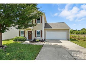 Charming two-story home with an attached garage, a well-maintained lawn, and a welcoming front entrance at 8152 Chilkoot Ln, Locust, NC 28097
